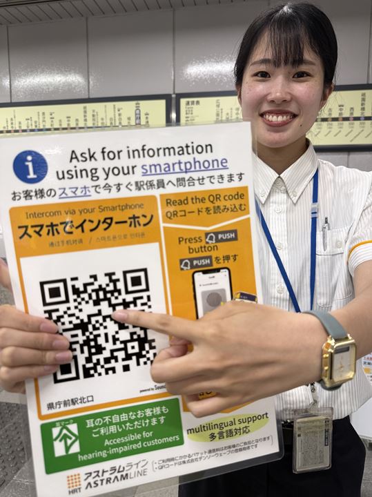 スマートフォンを使ったチャットサービスを紹介する県庁前駅の係員