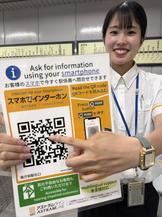 スマートフォンを使ったチャットサービスを紹介する県庁前駅の係員