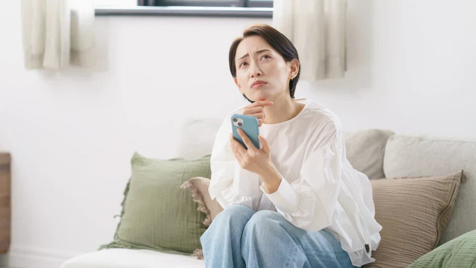 スマホを片手に悩む女性