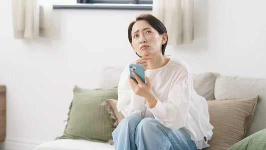 スマホを片手に悩む女性