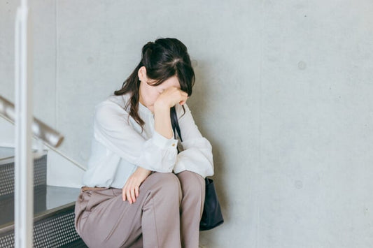 めまいで階段に座る女性