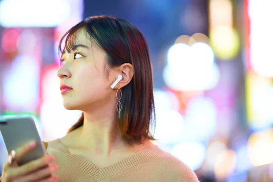 街中でイヤホンをしてスマホを操作する女性