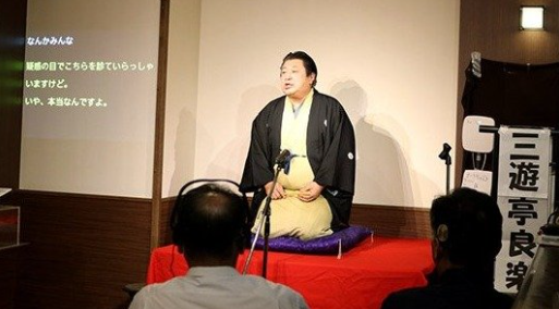リアルタイムで字幕が表示される中、落語を披露する三遊亭良楽さん＝アピアショッピングセンター