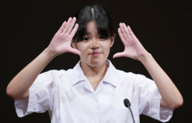 手話でスピーチをする愛媛県立松山聾（ろう）学校の村上黎央菜さん=2026年8月16日午後1時54分、東京都千代田区の有楽町朝日ホール、瀬戸口翼撮影
