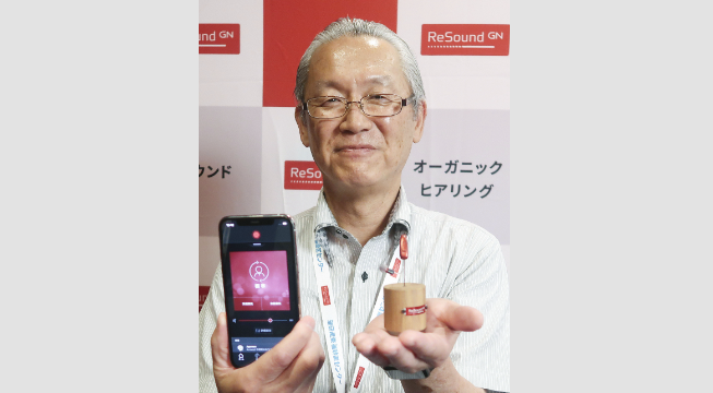無線通信「オーラキャスト」に対応した補聴器を紹介する理研産業の桜井雅之取締役＝7月、愛知県みよし市