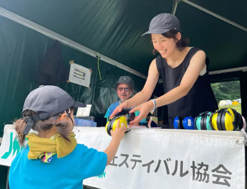 遮音用の耳当てを子どもに渡す日本ミュージックフェスティバル協会のスタッフら＝新潟県湯沢町で2026年7月24日午前11時45分、入江直樹撮影