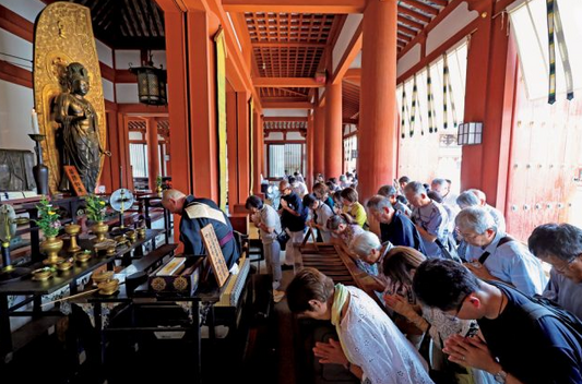 中央に薬師如来、向かって右に日光菩薩、左に月光菩薩を配置した金堂 。参加者はお経を唱える大谷さんとともに参拝した。