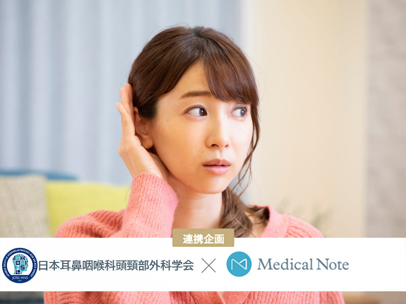 片耳を手で押さえる女性